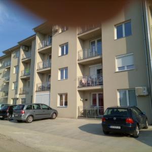 three cars parked in a parking lot in front of a building at Apartman Miloš in Soko Banja