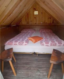 a bed in a wooden cabin with two chairs at Krampez in Kobarid