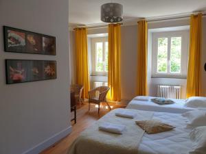 a hotel room with two beds and two windows at Gîte Les Bartavelles in Jausiers