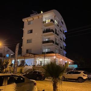 un edificio blanco alto con coches estacionados frente a él en SORAL APART en Demre