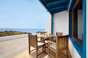 einen Tisch und Stühle auf einem Balkon mit Meerblick in der Unterkunft Welling in Punta de Mujeres