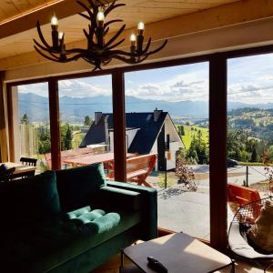 a living room with a green couch and a large window at Domki Widokowelove z widokiem na panoramę Tatr - mountain view in Gliczarów