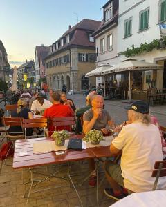 um grupo de pessoas sentadas em mesas num restaurante ao ar livre em Hotel Neuhauser em Volkach