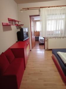 uma sala de estar com um sofá vermelho e uma televisão em Chergata Guest House em Zheglitsa