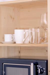 ein Regal mit Tassen und Gläsern auf der Mikrowelle in der Unterkunft Birtok Houses- twin no 1 for 2 people in Borzont