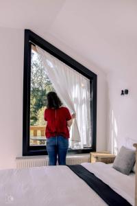 a woman looking out the window of a bedroom at Birtok Houses- twin no 1 for 2 people in Borzont