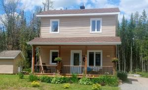 ein Haus mit einer Veranda auf der Vorderseite mit einer Terrasse in der Unterkunft Chalet Mathis in Saint-Raymond