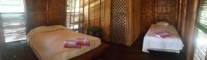 a room with two beds in a wooden cabin at Eco-Hotel Playa Quilombo in Las Lisas
