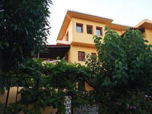 una casa amarilla con árboles delante de ella en Vasileiou, en Kala Nera