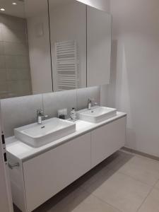 a white bathroom with two sinks and a mirror at Apartment Augenweide in Annenheim