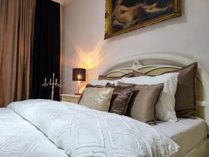 a bedroom with a white bed with a painting on the wall at Apartments Vila White House in Pančevo