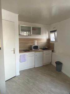 a small kitchen with white cabinets and a microwave at Le Stud' Joli appartement lumineux en plein centre ville in Cherbourg en Cotentin