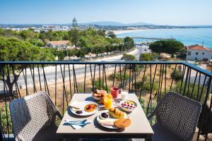 a table with food on a balcony with a view of the ocean at Apartamentos Marvela in Lagos