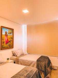 Pokój z dwoma łóżkami i obrazem na ścianie w obiekcie Villa Candombá w mieście Alto Paraíso de Goiás