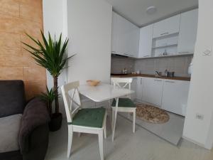 a white kitchen with a table and chairs and a couch at Apartman Kerkez in Soko Banja