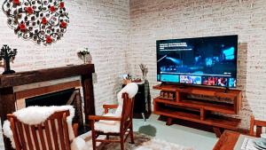 un salon avec une télévision et une cheminée dans l'établissement Chalé Villa Magrini, à Monte Verde