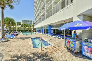 a pool with a blue umbrella and chairs and a building at 2 Story Direct Oceanfront Penthouse- Sandy Beach Resort 1116- Sleeps 6! in Myrtle Beach