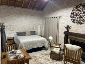a bedroom with a bed and a table and a fireplace at Chalé Villa Magrini in Monte Verde
