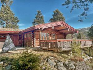 eine Blockhütte im Wald mit einer Veranda in der Unterkunft Timber Lodge in Uvdal Skisenter VIEW/WIFI in Sønstebø