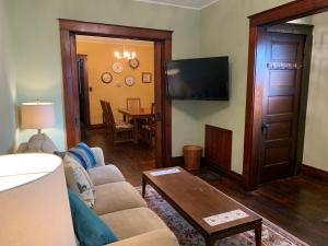 a living room with a couch and a flat screen tv at Red Brick Inn - Walk to the Falls, the Casino and all Downtown Restaurants in Niagara Falls