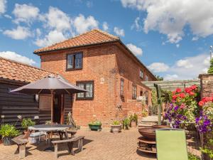 a brick house with a table and an umbrella at Punch Cottage in Little Glenham