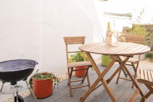 Una mesa y una silla de madera en un patio con parrilla de barbacoa. en Highfield House - 1 Bed-Sleeps 2-TJS20HH, en Ilfracombe