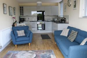 a living room with two blue chairs and a kitchen at Lovely 1 bedroom basement apartment with stunning views in Bodfari