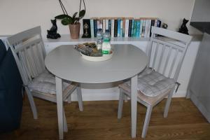 una mesa blanca con 2 sillas y un estante para libros en Lovely 1 bedroom basement apartment with stunning views, en Bodfari