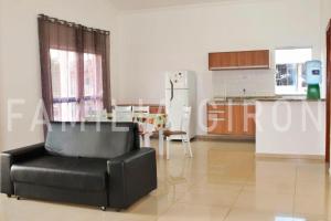 a living room with a black chair and a kitchen at Flats a 100 mts da Praia in Porto Seguro
