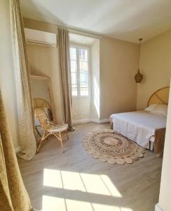 um quarto com uma cama, uma cadeira e uma janela em L'île rousse, hypercentre à 100 m de la plage em L'Île-Rousse