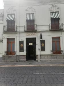 a white building with a door and a sign that reads asylum at Azcami Boutique Hotel in Puebla