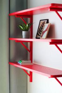 a red shelf with books and a plant on it at Kwadrat Hallera in Gdańsk