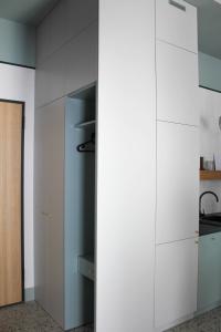 a kitchen with white cabinets and a sink at Kwadrat Hallera in Gdańsk