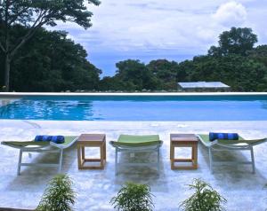 a swimming pool with two lounge chairs and a table at Tree of Life Cabinas in Dominical