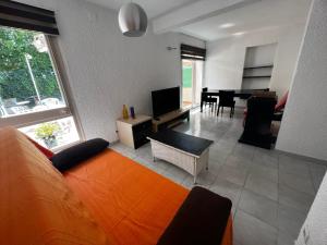 sala de estar con sofá naranja y TV en Apartamentos La Isla, en Lloret de Mar