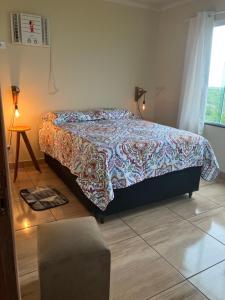 a bedroom with a bed and a table and a window at Chalé Pedro & Carmelita in Serra de São Bento