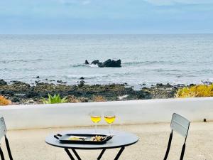 una mesa con dos copas de vino en la playa en Canaryislandshost l Lava y Mar Lanzarote, en Punta Mujeres