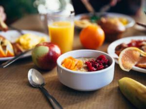 een tafel met een schaal ontbijtgranen met fruit en sinaasappelsap bij Nordic Relax House - Stonehouse in Sjöbo