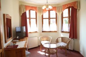 - un salon avec une table, des chaises et des fenêtres dans l'établissement Hajdú Kastély Hotel, à Hajdúszoboszló