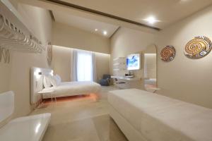 a hotel room with two beds and a television at Palazzo Gatto Art Hotel & SPA - BW Premier Collection in Trapani