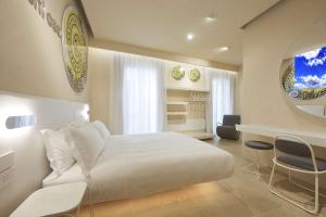 a bedroom with a white bed and a table and chairs at Palazzo Gatto Art Hotel & SPA - BW Premier Collection in Trapani