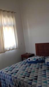 a bedroom with a bed with a blue and white quilt at Flats a 100 mts da Praia in Porto Seguro
