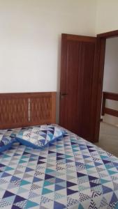 a bedroom with a bed with a blue and white quilt at Flats a 100 mts da Praia in Porto Seguro