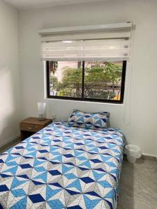 a bedroom with a blue and white bed and a window at Casa tradicional - Cerca a la Zona Rosa in Envigado