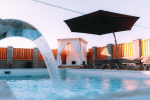 a pool with an umbrella and chairs and a swimming pool at Cartagena Villa & Spa in Brčko