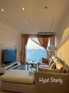 Hyat Hostel & Suites في الإسكندرية: غرفة معيشة مع أريكة وتلفزيون