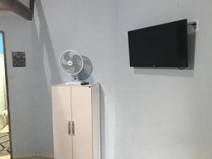 a fan sitting on top of a cabinet with a tv at Chalé Raio De Sol in Vale do Capao