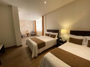 Habitación de hotel con 2 camas y sala de estar. en Hotel Casa Faroles Centro Histórico, en Zacatecas