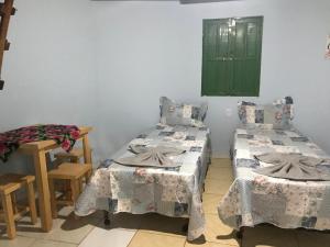 a room with two beds and a green door at Chalé Raio De Sol in Vale do Capao