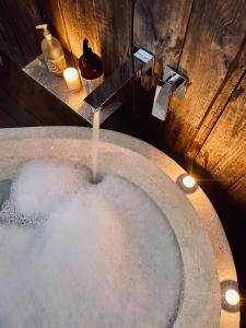 a bath tub filled with water next to a wooden wall at Luxury 6 metre Bell Tent & Outdoor Bathroom, WIFI, TV and firepit, in Coodanup